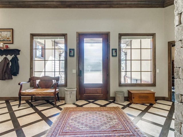 entrance foyer with crown molding, a stone fireplace, and baseboards