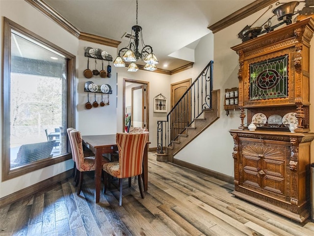 dining room with visible vents, ornamental molding, wood finished floors, stairs, and a notable chandelier