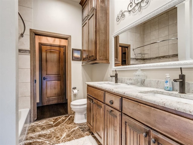 full bath featuring toilet, double vanity, and a sink