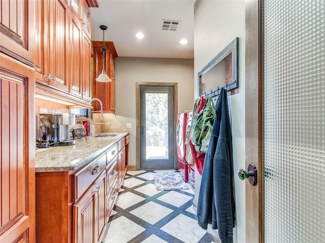 interior space featuring brown cabinets, a sink, pendant lighting, backsplash, and recessed lighting