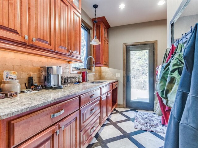 kitchen featuring decorative light fixtures, recessed lighting, decorative backsplash, a sink, and light stone countertops