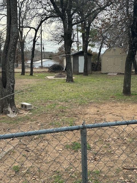 view of yard with fence, a storage unit, and an outbuilding