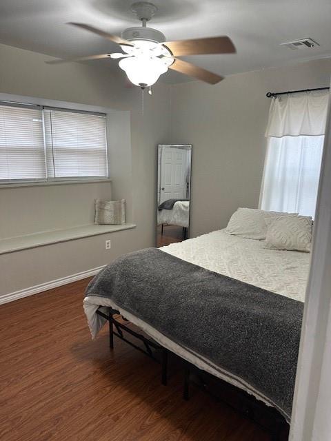 bedroom with a ceiling fan, visible vents, and wood finished floors