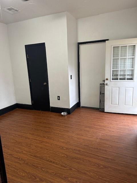 empty room featuring baseboards, visible vents, and wood finished floors