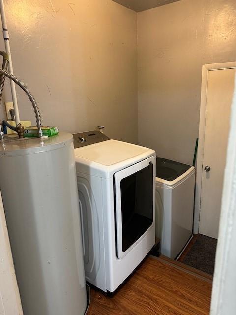 clothes washing area with water heater, laundry area, separate washer and dryer, and wood finished floors