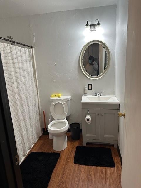 bathroom featuring toilet, a shower with curtain, wood finished floors, and vanity