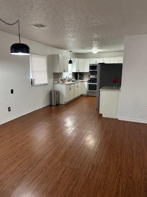 kitchen featuring dark wood-style floors, appliances with stainless steel finishes, light countertops, and pendant lighting