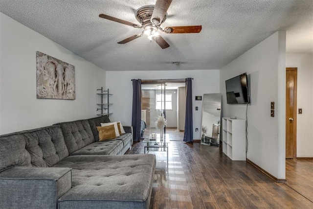 living area with dark wood-style floors, a textured ceiling, baseboards, and a ceiling fan