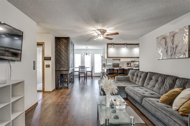 living room featuring a textured ceiling, dark wood-type flooring, and ceiling fan with notable chandelier