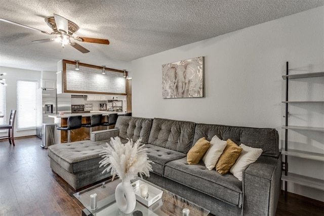 living area with a textured ceiling, dark wood-type flooring, and a ceiling fan