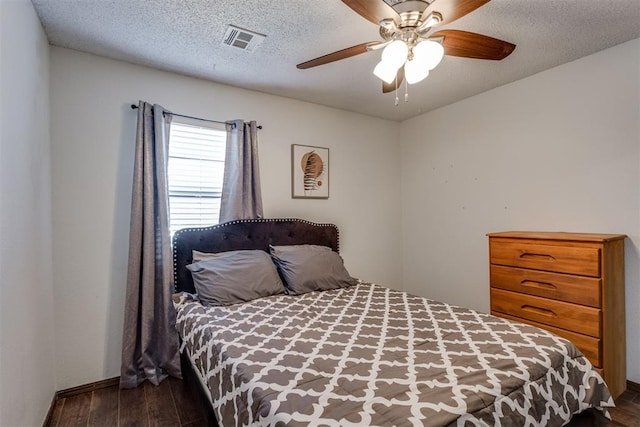 bedroom featuring a textured ceiling, ceiling fan, dark wood-style flooring, and visible vents