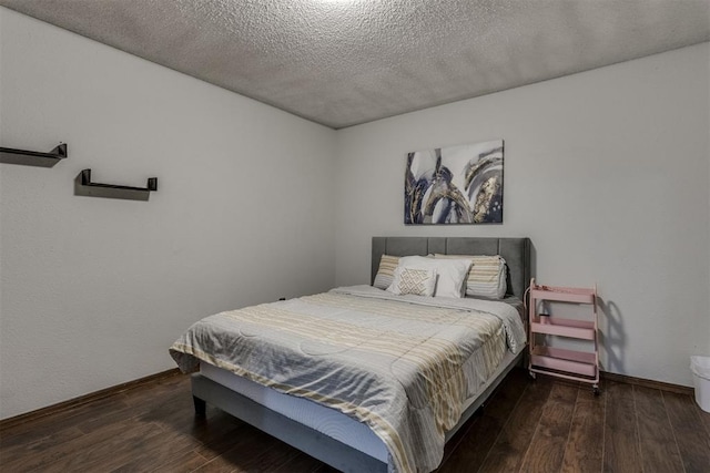 bedroom with a textured ceiling, baseboards, and wood finished floors