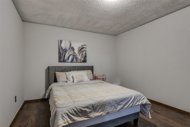 bedroom with a textured ceiling, baseboards, and wood finished floors