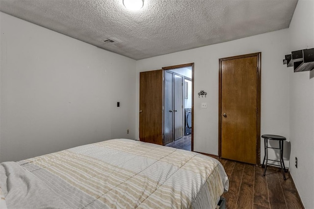 bedroom with visible vents, dark wood finished floors, and a textured ceiling