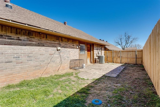 back of house with a fenced backyard, cooling unit, a shingled roof, and brick siding