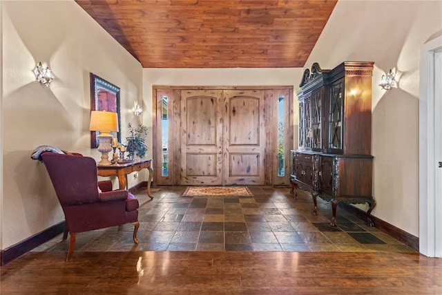 entrance foyer with wooden ceiling, vaulted ceiling, baseboards, and stone tile flooring