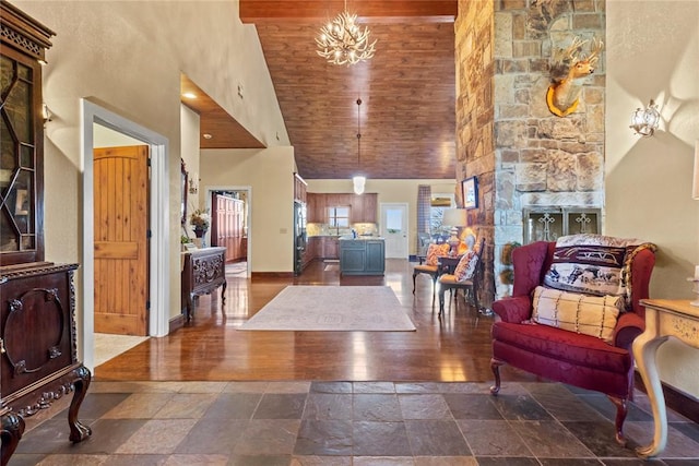 interior space with baseboards, a high ceiling, stone tile flooring, wooden ceiling, and a notable chandelier