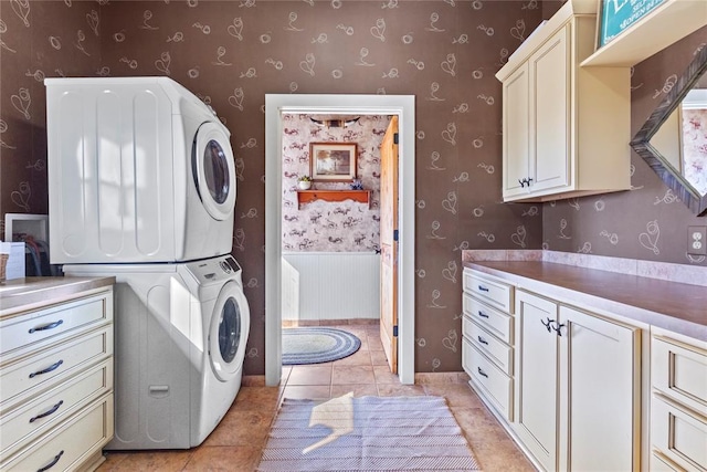 washroom with wallpapered walls, light tile patterned floors, cabinet space, and stacked washer and clothes dryer