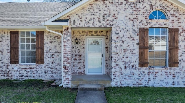 entrance to property with brick siding and roof with shingles