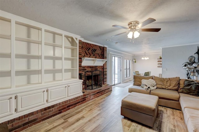 living room with light wood finished floors, a fireplace, ornamental molding, a textured ceiling, and ceiling fan with notable chandelier