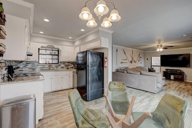 kitchen featuring ceiling fan with notable chandelier, a sink, tasteful backsplash, white cabinetry, and freestanding refrigerator