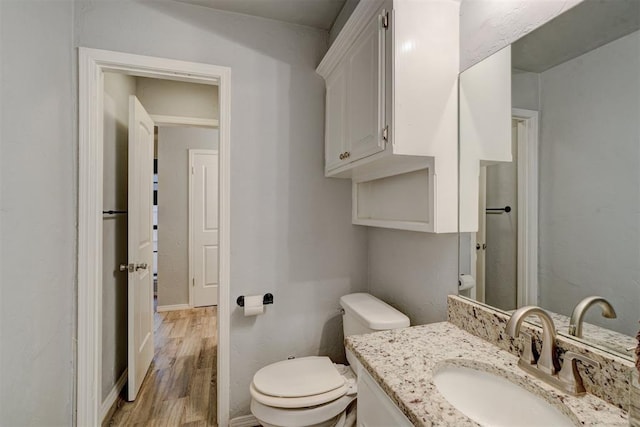 bathroom featuring toilet, vanity, baseboards, and wood finished floors