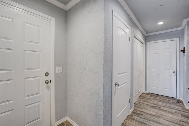 doorway to outside with light wood finished floors, crown molding, baseboards, and a textured wall