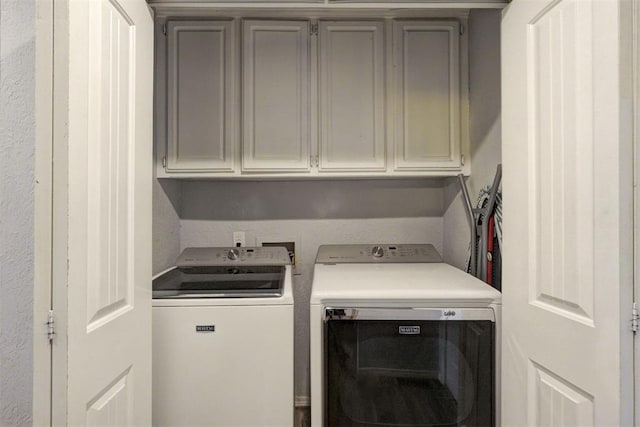 clothes washing area featuring cabinet space and washer and clothes dryer