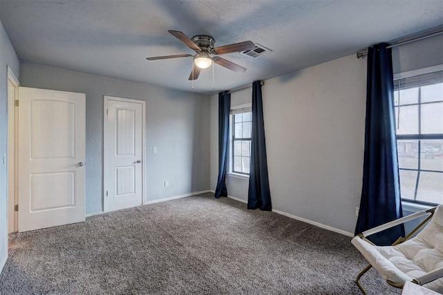 unfurnished bedroom featuring visible vents, carpet floors, baseboards, and a ceiling fan