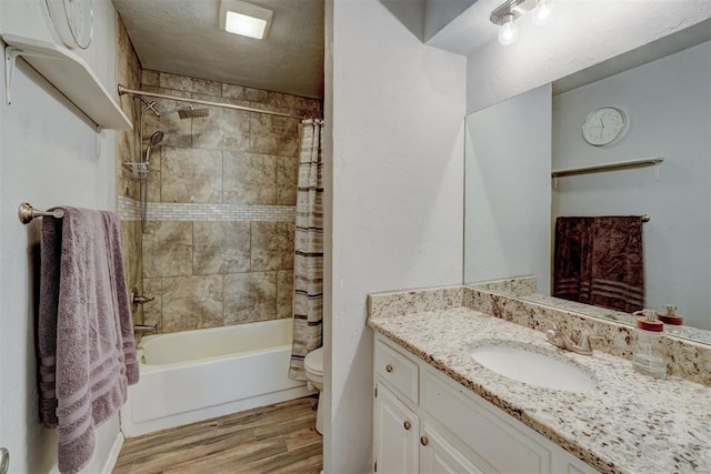 full bathroom featuring toilet, shower / bath combo, wood finished floors, a textured ceiling, and vanity