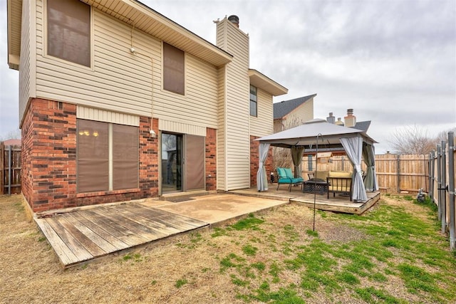 rear view of property featuring a deck, a gazebo, a fenced backyard, and brick siding