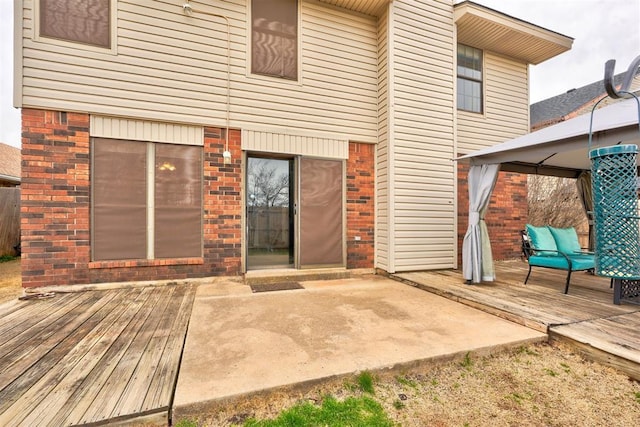 rear view of house featuring a gazebo, brick siding, and a wooden deck