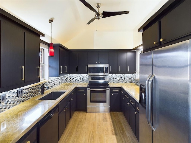 kitchen with appliances with stainless steel finishes, decorative light fixtures, a sink, light wood-type flooring, and backsplash