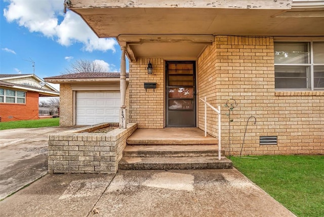 view of exterior entry with an attached garage, crawl space, concrete driveway, and brick siding