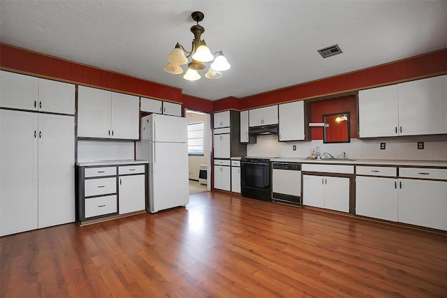 kitchen featuring white appliances, visible vents, under cabinet range hood, and white cabinets