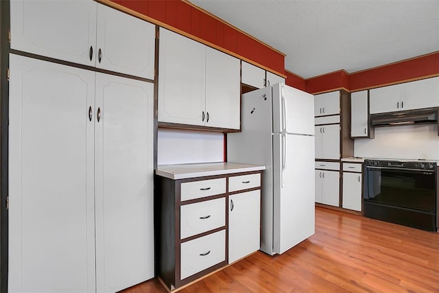 kitchen featuring light wood finished floors, light countertops, freestanding refrigerator, under cabinet range hood, and black / electric stove