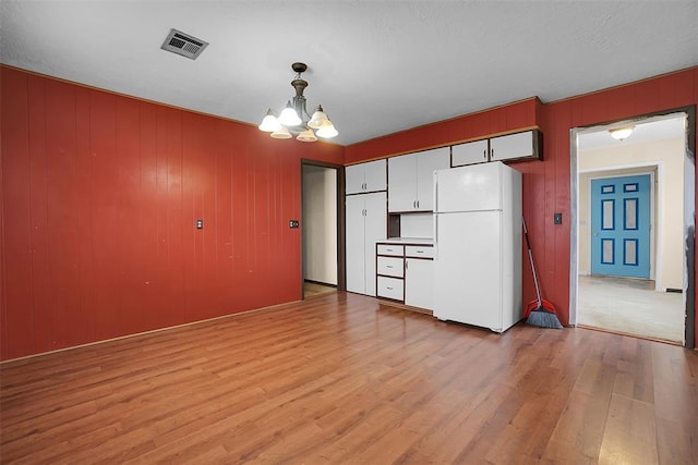 interior space featuring light wood-style floors, a chandelier, and visible vents