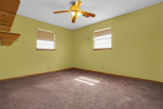 carpeted spare room with baseboards, visible vents, and ceiling fan