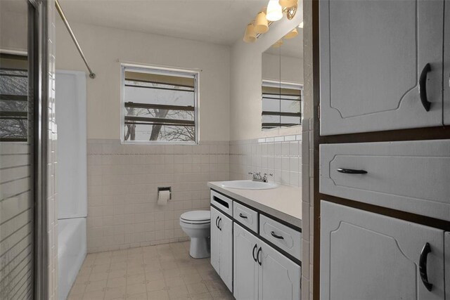 full bathroom with toilet, a wainscoted wall, vanity, tile walls, and tile patterned floors