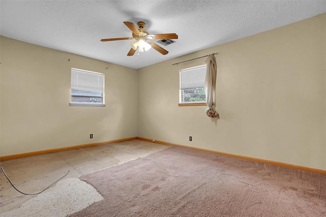 empty room featuring a ceiling fan, visible vents, a textured ceiling, and baseboards