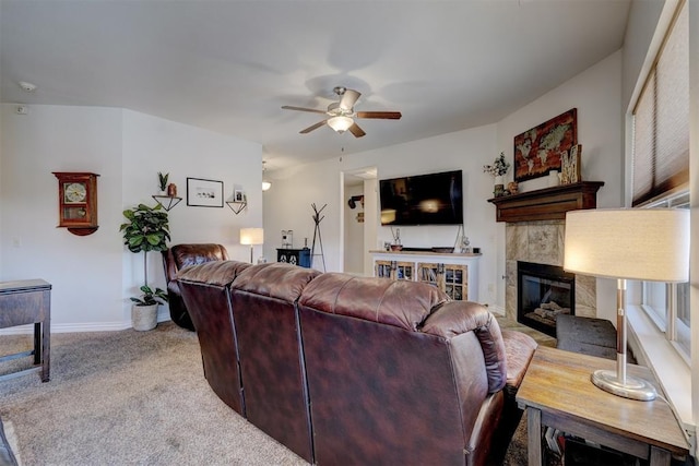 living room with a tiled fireplace, baseboards, carpet floors, and ceiling fan