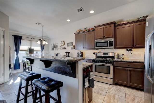 kitchen with visible vents, a kitchen bar, appliances with stainless steel finishes, and decorative backsplash