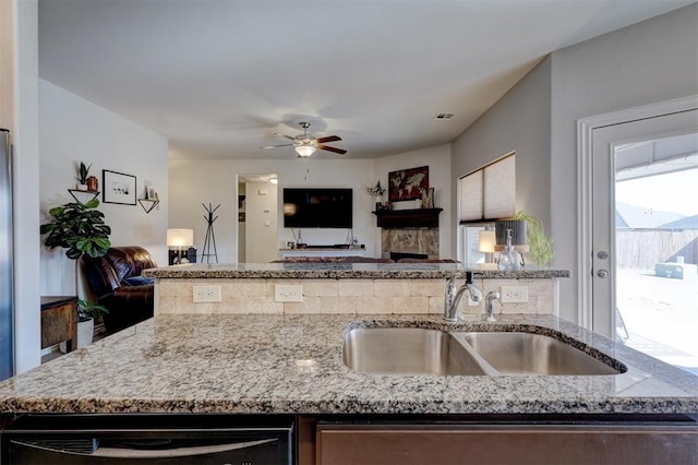 kitchen with light stone countertops, open floor plan, and a sink