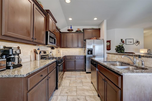 kitchen featuring backsplash, light stone countertops, stainless steel appliances, and a sink