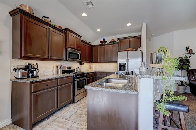 kitchen with visible vents, a kitchen island with sink, a sink, decorative backsplash, and stainless steel appliances