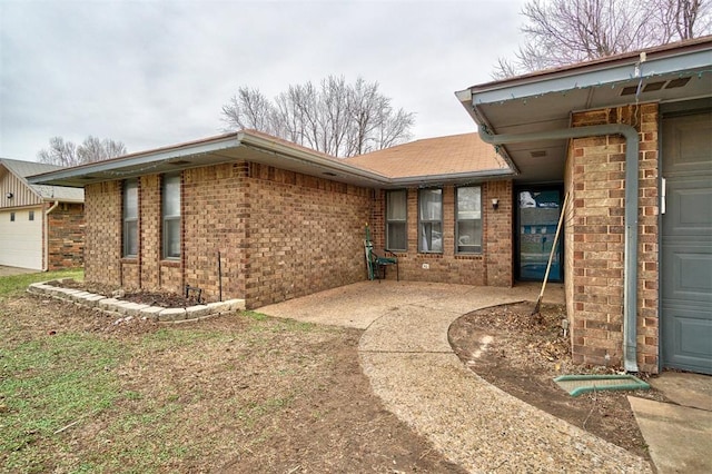 property entrance with brick siding and an attached garage