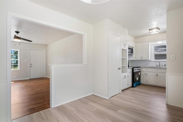 kitchen featuring light wood finished floors, a sink, light countertops, range with electric stovetop, and stainless steel microwave