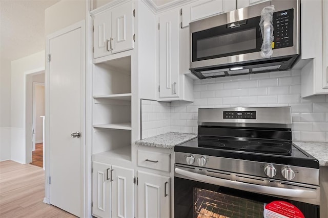 kitchen with white cabinets, light stone countertops, light wood finished floors, and stainless steel appliances