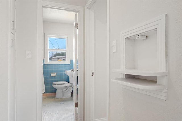 bathroom featuring a wainscoted wall, toilet, tile walls, and tile patterned flooring