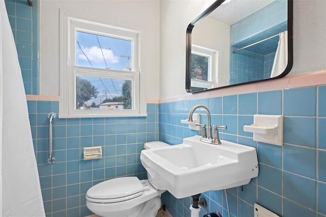 full bath with a shower with curtain, a sink, wainscoting, tile walls, and toilet